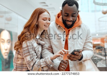 young happy girl pointing to the screen showing her bearded boyfriend sales couple choosing goods, lifestyle.hobby interests red-haired girl showing something on smart phone to handsome boyfriend