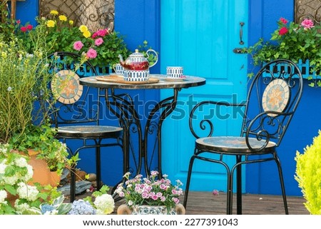 porcelain set for tea or coffee on table in cozy backyard flower garden. Summer outdoor party setting Royalty-Free Stock Photo #2277391043