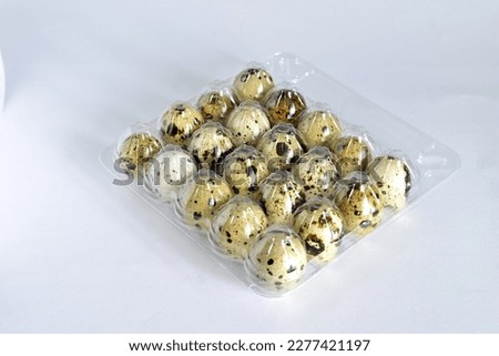 The picture shows colorful quail eggs, which lie in rows in a transparent boat, top view.