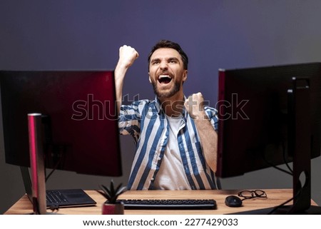 Overjoyed man gamer playing computer game at home, winning, celebration concept  Royalty-Free Stock Photo #2277429033