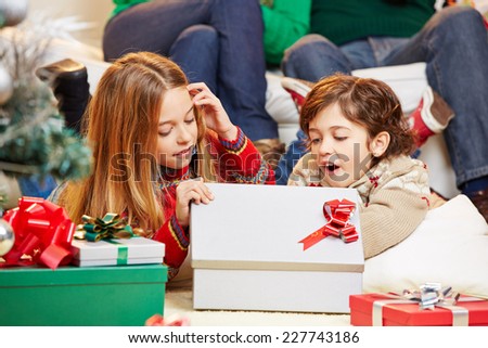 Two happy children opening gifts together at christmas eve