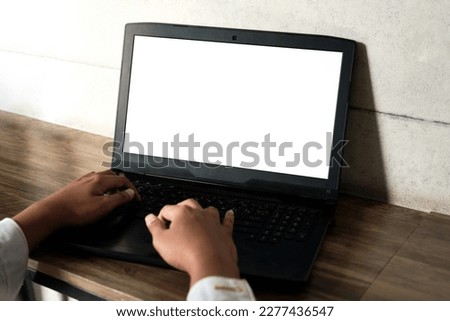 Mockup image of a man using and working on laptop computer with a blank white screen on wooden table