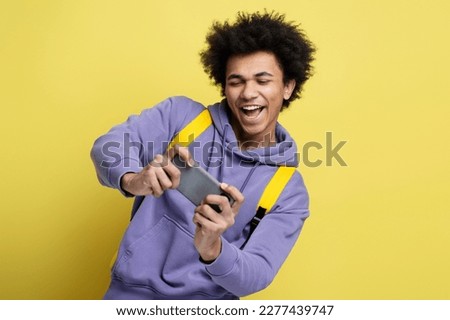 Excited African American man using smartphone playing mobile game celebration success isolated on yellow background. Overjoyed hipster shopping online, sports betting, win money