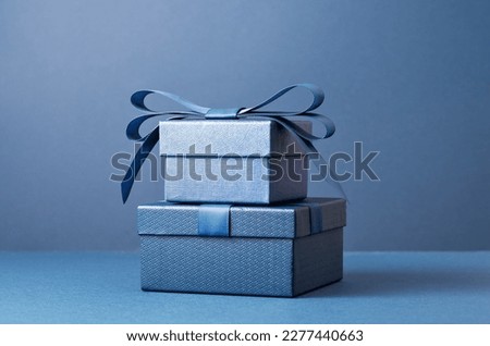 Two Luxury gift boxes with a blue bow on dark blue. Side view monochrome . Fathers day or Valentines day gift for him. Corporate gift concept or birthday party. Festive sale copy space Royalty-Free Stock Photo #2277440663