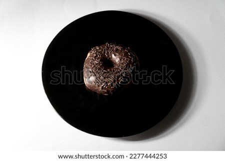 chocolate donut in black plate on white background. Top view