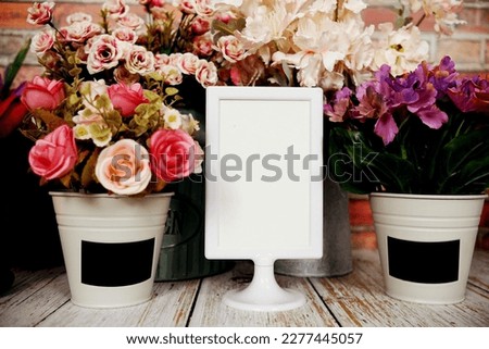 Mock up empty paper card with artificial flower decoration on wooden background