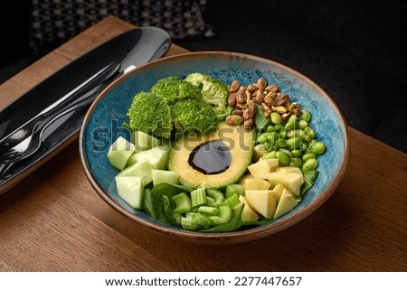 Healthy green vegetarian buddha bowl salad with grilled vegetables and quinoa, avocado, brussels sprouts, asparagus, edamame beans close-up on the table, serving in a restaurant, menu food concept.