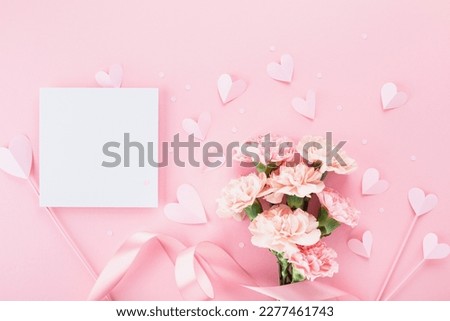 Bouquet of beautiful pink carnation flowers, hearts and greeting card on pastel table for Happy mothers day. Flat lay.