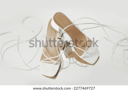 Creative studio shot of white strappy lace up block heel sandals, product photography Royalty-Free Stock Photo #2277469727