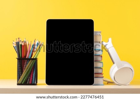 Tablet with colorful pencils and stack of books. With blank screen for your text or app