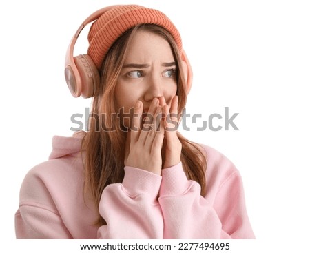 Worried young woman in headphones on white background, closeup