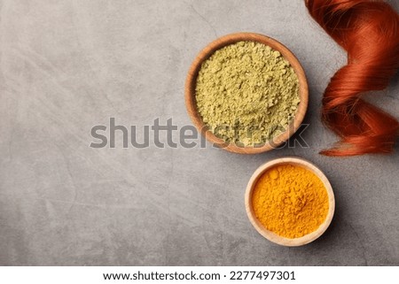 Red strand, henna and turmeric powder on grey table, flat lay with space for text. Natural hair coloring