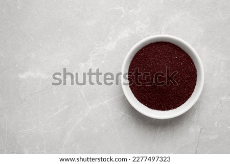 Bowl with dark red food coloring on light grey marble table, top view. Space for text