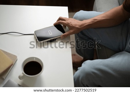 Man hands Charging mobile phone battery with low battery. plugging a charger in a smart phone  with energy bank powerbank charger Modern lifestyle energy technology.
