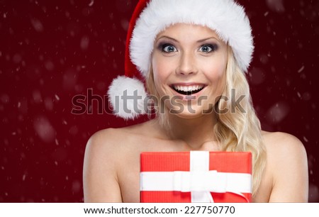 Pretty woman in Christmas cap hands present wrapped with red paper, isolated on purple