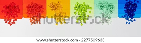 multicolored transparent plastic resin granulates with its color sample plates on white Royalty-Free Stock Photo #2277509633
