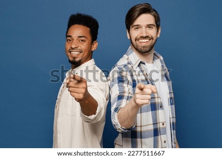 Side view young two friends happy fun men wear white casual shirt together point index finger camera on you motivating encourage isolated plain dark royal navy blue background People lifestyle concept