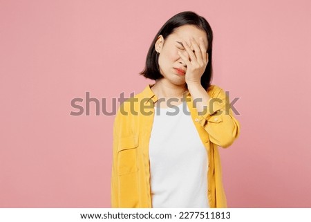 Young sad woman of Asian ethnicity wears yellow shirt white t-shirt put hand on face facepalm epic fail mistaken omg gesture isolated on plain pastel light pink background studio. Lifestyle concept Royalty-Free Stock Photo #2277511813