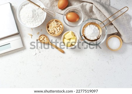 Baking and cooking ingredients, butter flour eggs and slivered almond with digital scale on marble background, copy space, top view Royalty-Free Stock Photo #2277519097