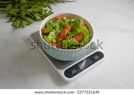 Plate with salad, kitchen scales on a light background