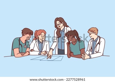 Clinic staff meeting, with doctors sitting at table and head physician giving instructions to medical workers. Men and women working in clinic choosing tactics for treatment of patient