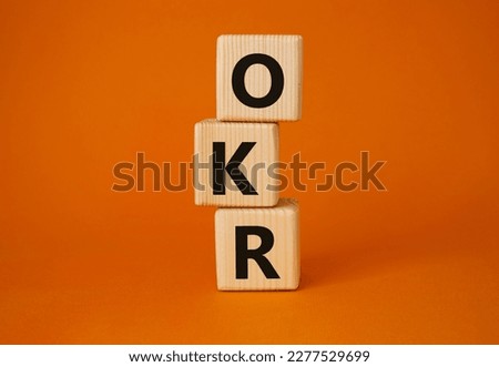 OKR objectives and key results symbol. Wooden cubes with words OKR objectives and key results. Beautiful orange background. Business and OKR objectives and key results concept. Copy space.