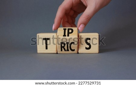 Tips and Tricks symbol. Businessman Hand turns cubes and changes word Tricks to Tips. Beautiful grey background. Business and Tips and Tricks concept. Copy space