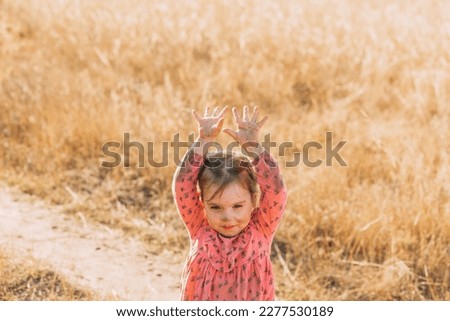 Little girl with a dirty face and dirty clothes in nature with her mom. Children playing outside with dirty hands.