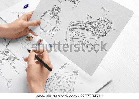 Jeweler with sketches of elegant jewelry at white wooden table, closeup Royalty-Free Stock Photo #2277534713