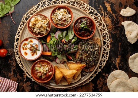 bahrain iftar and breakfast platter with samosa, raita, salad, bread, fruit chaat served in dish isolated on table top view of arabic breakfast Royalty-Free Stock Photo #2277534759