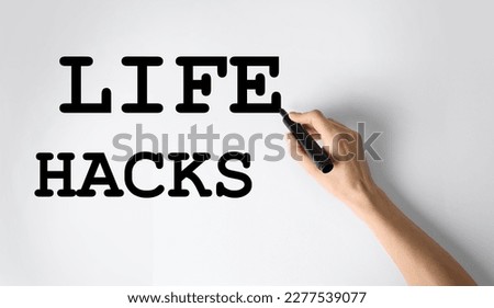 Woman writing words Life Hacks with marker on whiteboard, closeup