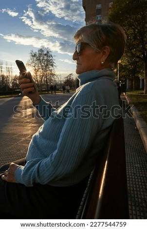 woman in her eighties talks on a cell phone at sunset