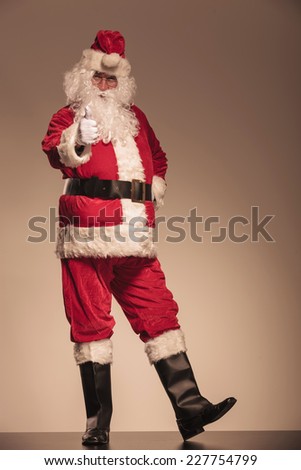 Full length picture of Santa Claus showing the thumbs up gesture.