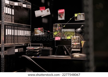 Private detective empty workplace with crime case evidences board hanging over desk. Police investigator office surrounded with murder scene photos and clues at night time