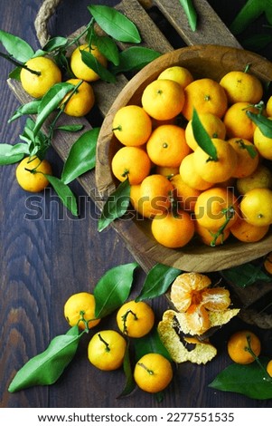 Mandarin orange on rustic wooden bowl and dark wooden background. Top view, copy space for text.