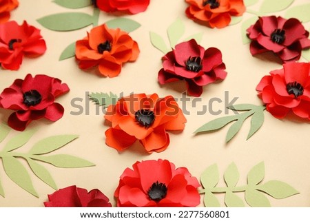 Paper poppy flowers with leaves on beige background, closeup