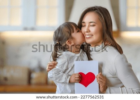 Happy mother's day. Child daughter congratulating her mother and giving her postcard.