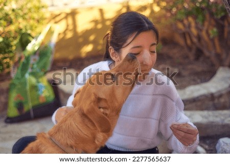 a dog kissing and licking a girl in the garden