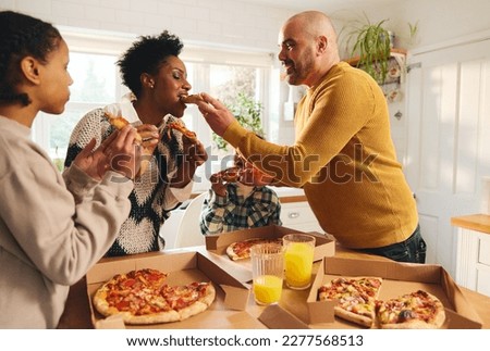 Family eating takeaway pizza at home, man feeding woman Royalty-Free Stock Photo #2277568513