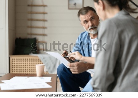 Middle aged senior old couple holding documents reading paper bills paying bank loan online, calculating pension fees, payments, taxes, planning family retirement money finances at home. Royalty-Free Stock Photo #2277569839