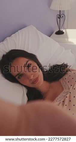 Close up, morning selfie of young beautiful woman lying in bed. Top view