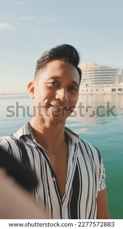 Close-up of young man standing on dock taking selfie with cell phone