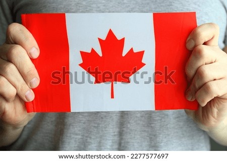 Close-up, the flag of Canada in the hands of a man.