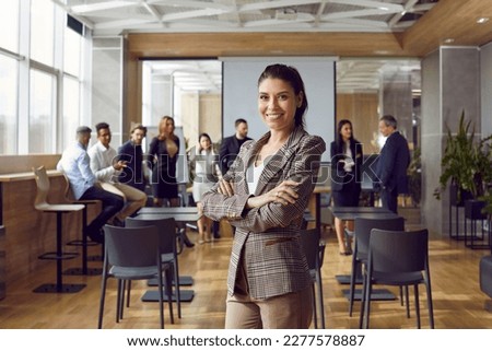 Happy professional business teacher after corporate training class for team of workers. Beautiful young woman in suit jacket standing in office conference room, looking at camera and smiling Royalty-Free Stock Photo #2277578887
