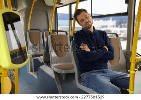 Tired man sleeping while sitting in public transport Royalty-Free Stock Photo #2277581529