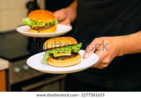 Homemade burgers with cheese , tomatoes, green salad leaf served on white plates.