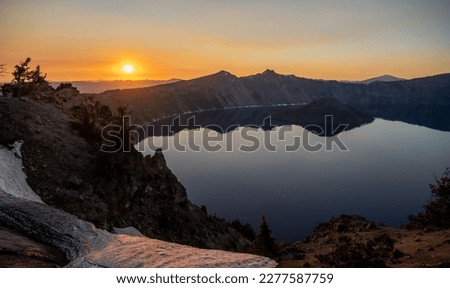 Rocky Cliffs Surround The Deep Blue Waters of Crater Lake In Summer at sunset Royalty-Free Stock Photo #2277587759