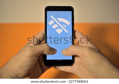 Smartphone in hand with no wifi network icon on display network unavailable without wi fi on coloured yellow and white background