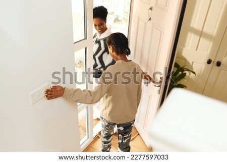 Teen girl turning off lightswitch and leaving house Royalty-Free Stock Photo #2277597033