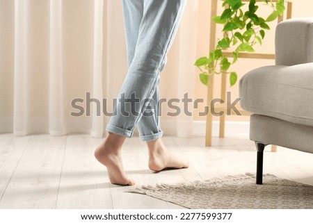 Woman stepping barefoot in room at home, closeup. Floor heating Royalty-Free Stock Photo #2277599377